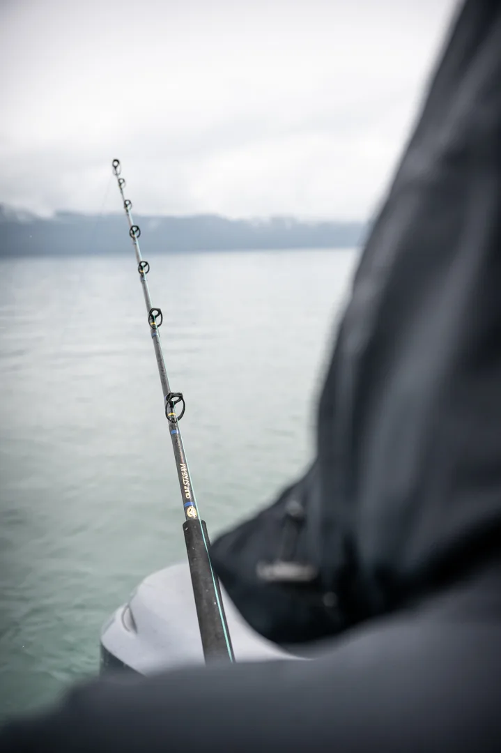Gulfstream fishing rod in gunwale holder, overcast water and misty mountains in background.